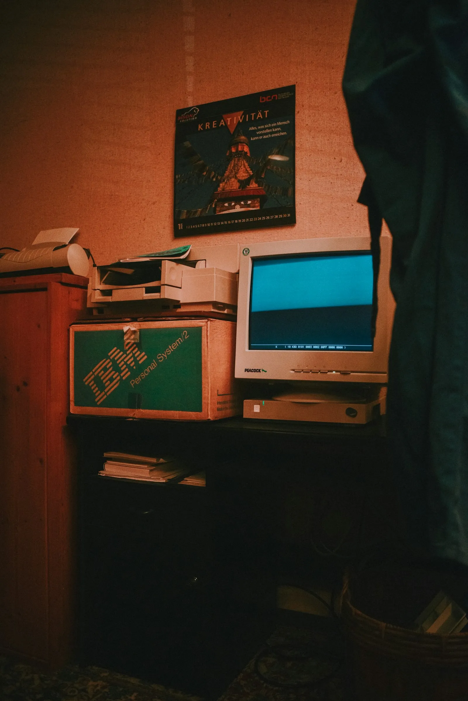 A CRT monitor glowing in a dim room next to an old IBM Personal System/2 box