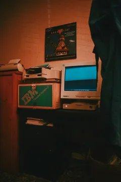 A CRT monitor glowing in a dim room next to an old IBM Personal System/2 box