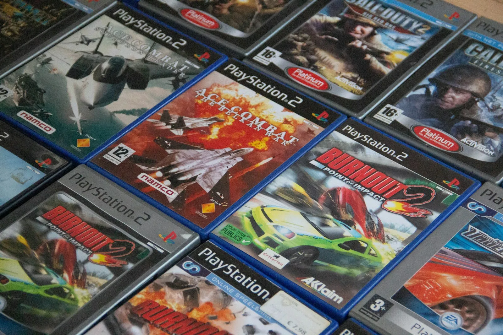 A pile of PlayStation 2 game cases, including Call of Duty 2 and Ace Combat